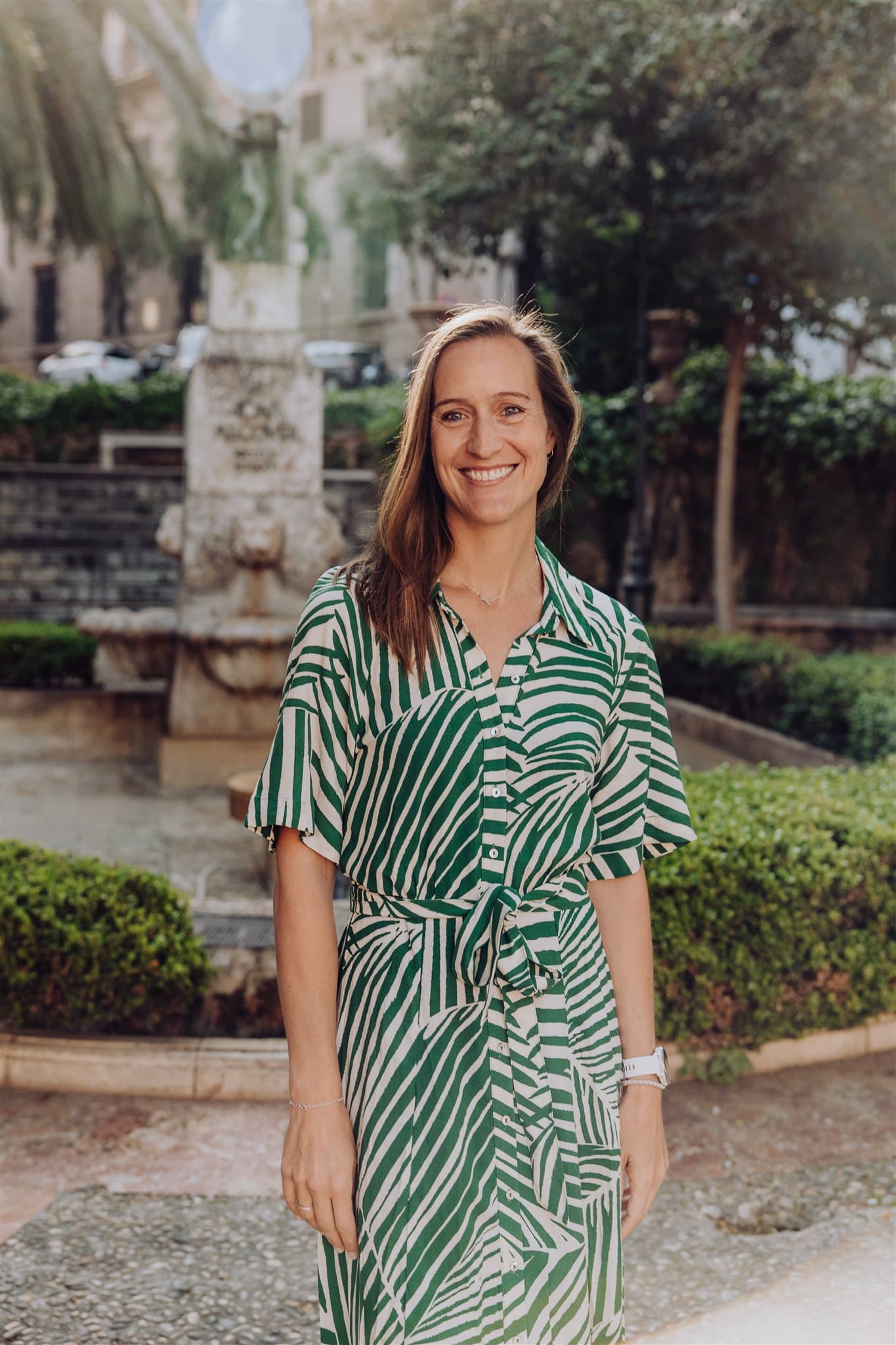 A person in a green and white striped dress standing in a garden setting